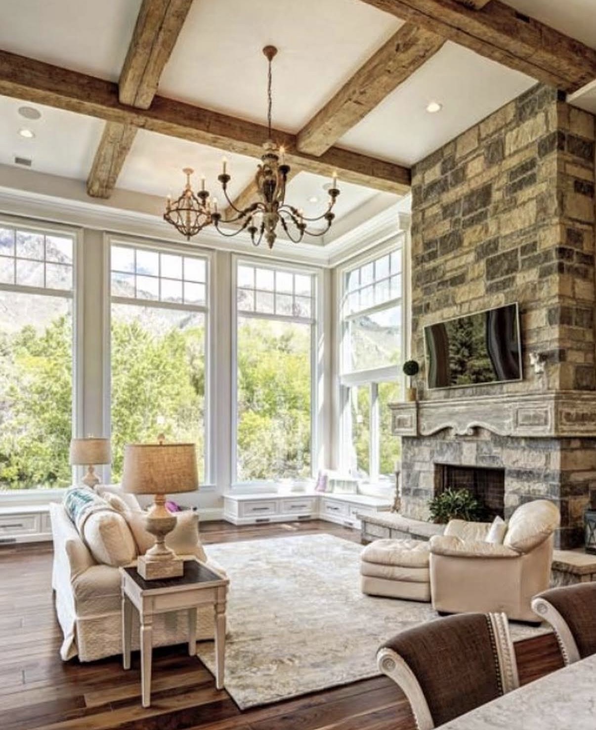 Light-filled custom living room with timber beams and a stone fireplace